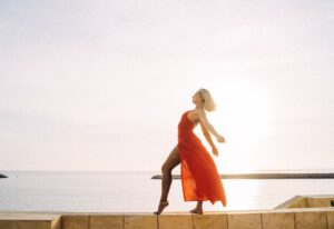 Woman dancing freely at sunset, representing feminine energy and self-reconnection.